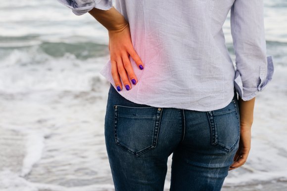 Lady holding her lower back because of lower back pain